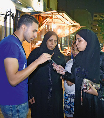 Ein Helfer verteilt Infozettel zu den Jobcentern an junge Menschen in den Straßen Kairos