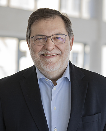 Ein Porträt von Peter Palesch, dem Landesdirektor der GIZ. Er hat ein freundliches Lächeln, trägt eine Brille, ein dunkles Jackett, ein hellblaues Hemd und hat mittellanges graues Haar und einen Bart.