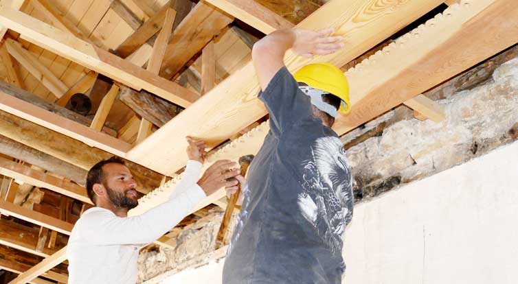 Die Zimmerleute arbeiten an der traditionellen Deckenvertäfelung.