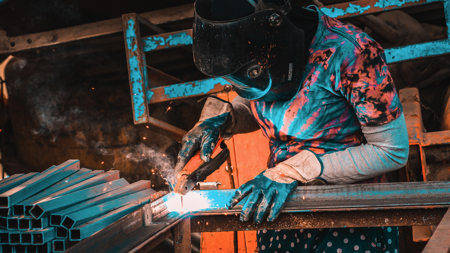 A female welder with mask and a welding machine