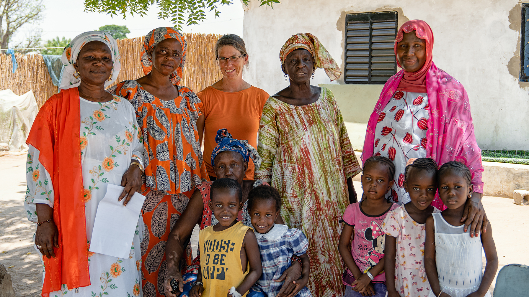 Eine Gruppe von Frauen und Kindern posiert für ein Foto im Freien, alle bunt gekleidet.