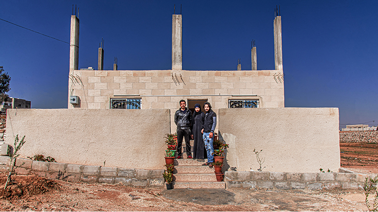 Sarah Qasim Hilal with her family in front of their new home