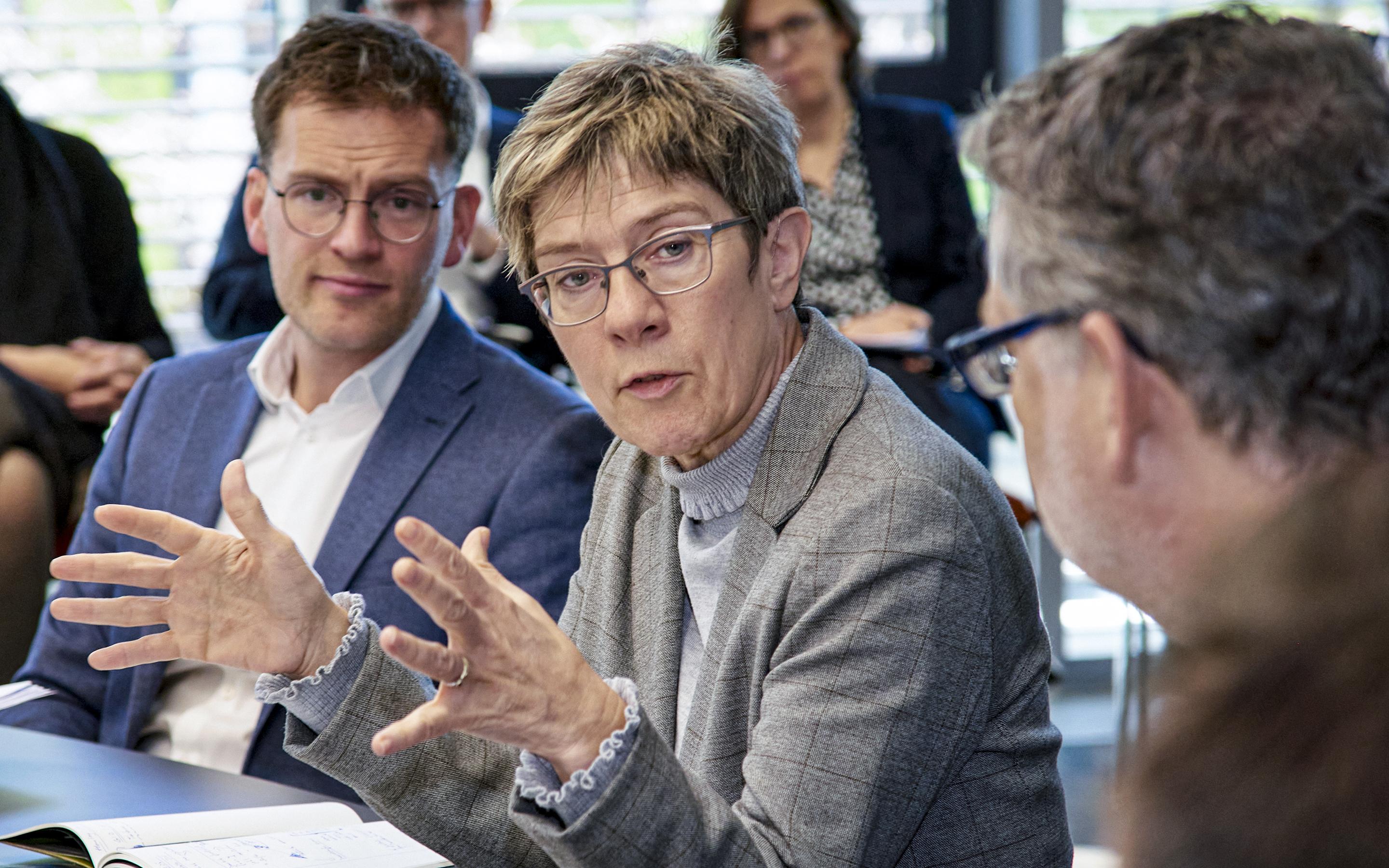 Gaby Gerster/GIZ Diskussion in einem Konferenzraum mit einer Frau im grauen Blazer, die mit Gestik spricht, umgeben von mehreren Personen in Businesskleidung, die aufmerksam zuhören.