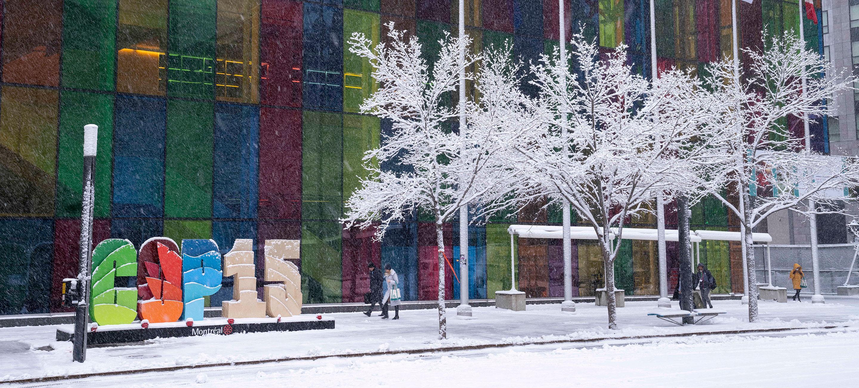 Bunte Häuserfront im Schnee mit Personen und Logo „COP15“