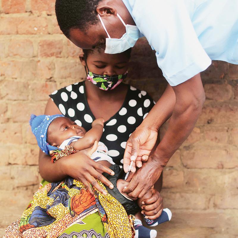 Arzt impft Baby im Arm der Mutter