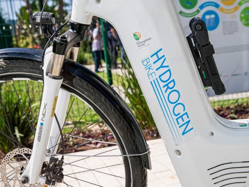 Fernando Souza/GIZ Brasil Nahaufnahme eines weißen Fahrrads mit der Aufschrift "Hydrogen Bike" am Rahmen, im Freien fotografiert.
