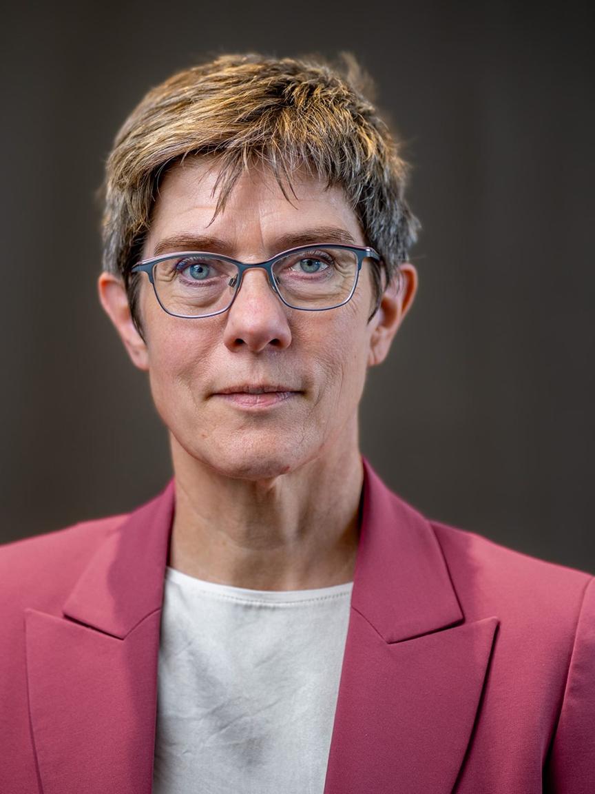 Global Perspectives Initiative gUG Porträt einer Frau mittleren Alters mit kurzen, gesträhnten Haaren, Brille, weißem Oberteil und rotem Blazer vor neutralem Hintergrund, die direkt in die Kamera blickt.